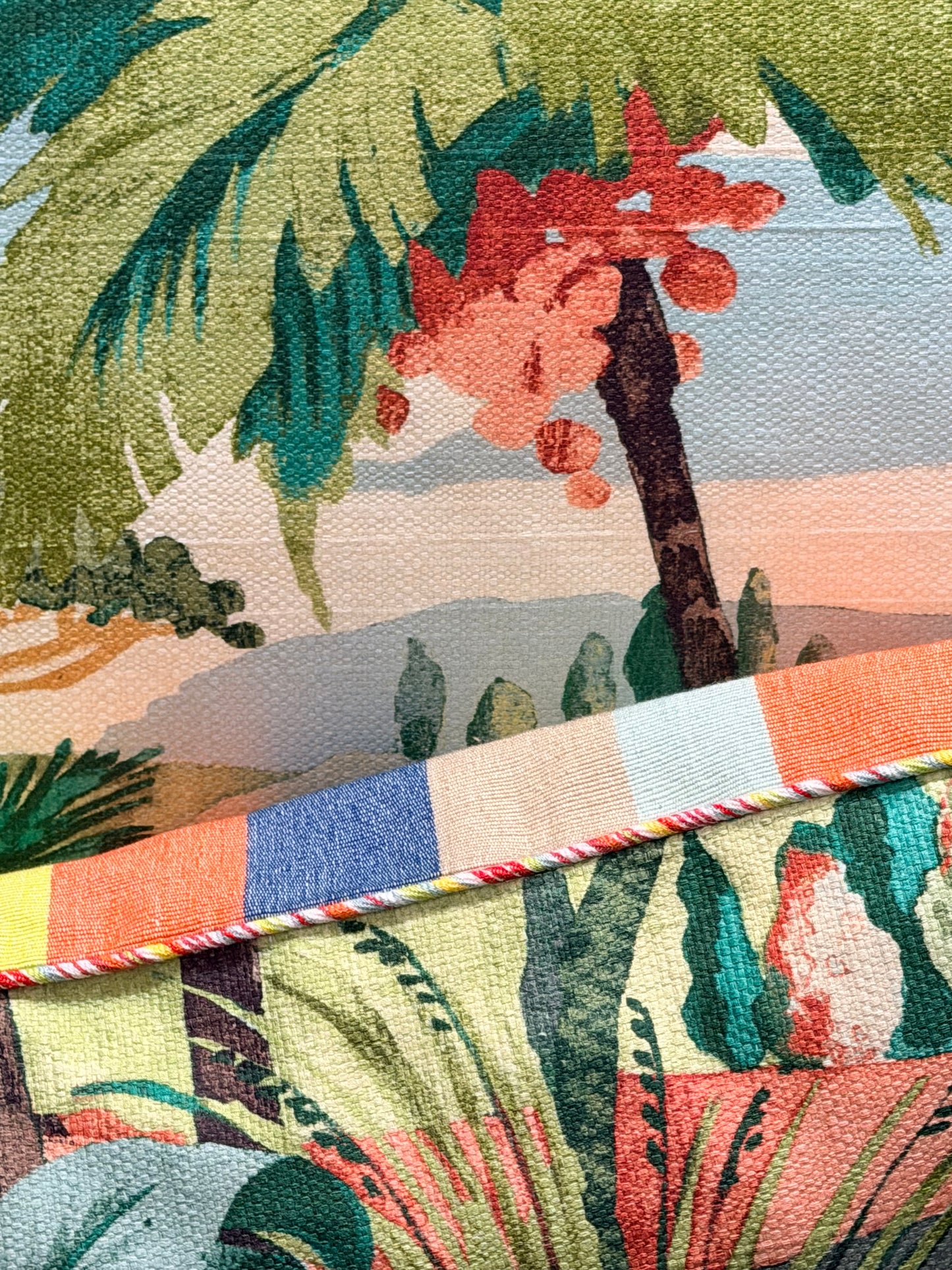 Close-up of a colorful fabric with tropical patterns and a branch.
