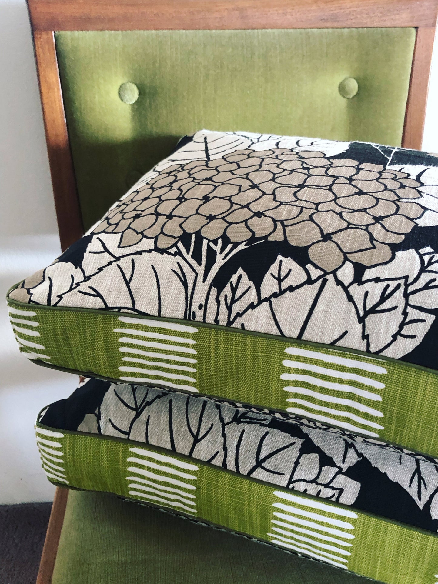 Stack of fabric samples with green, black, and white patterns on a chair.