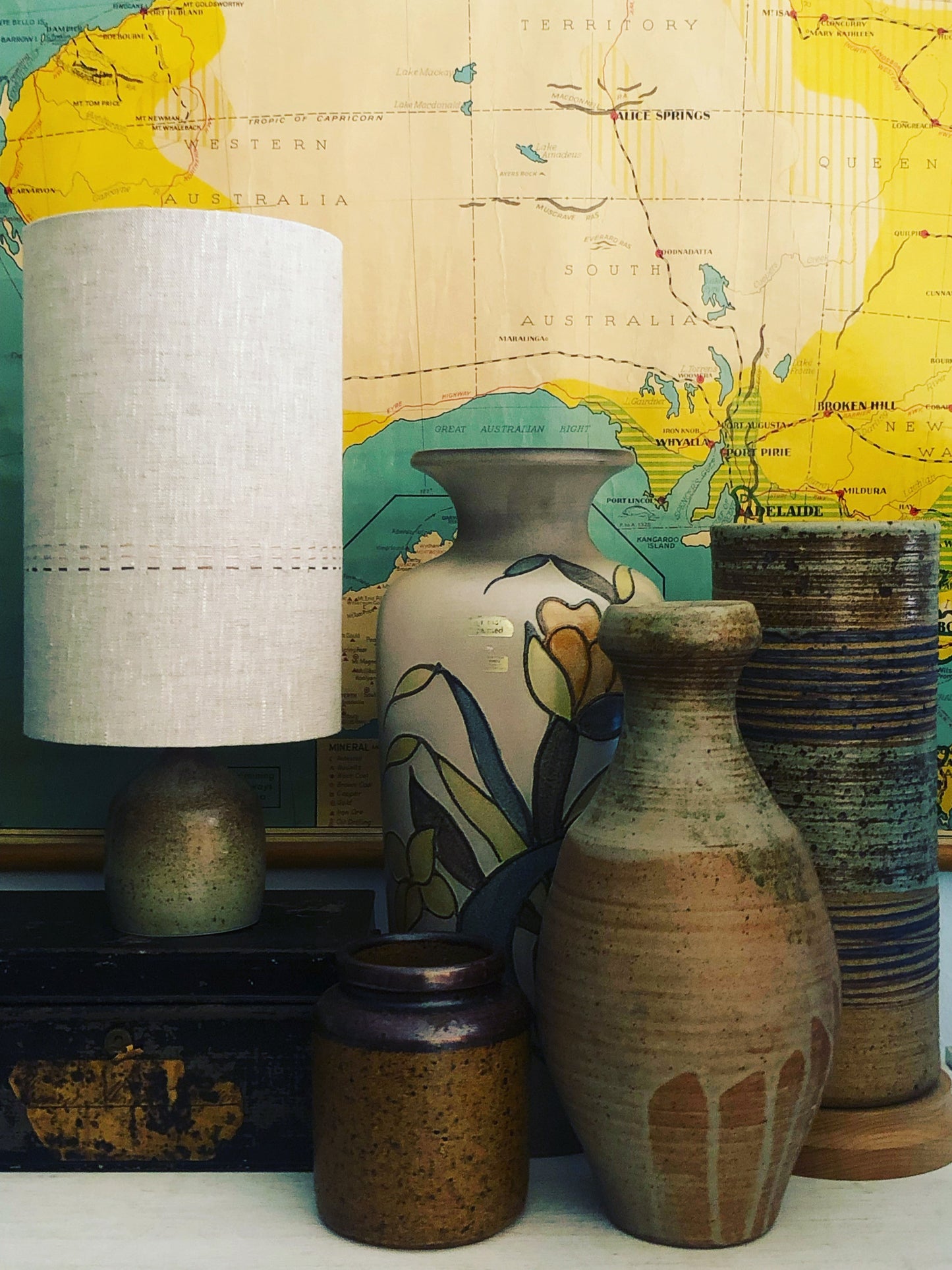 Collection of ceramic vases and a lamp against a map background