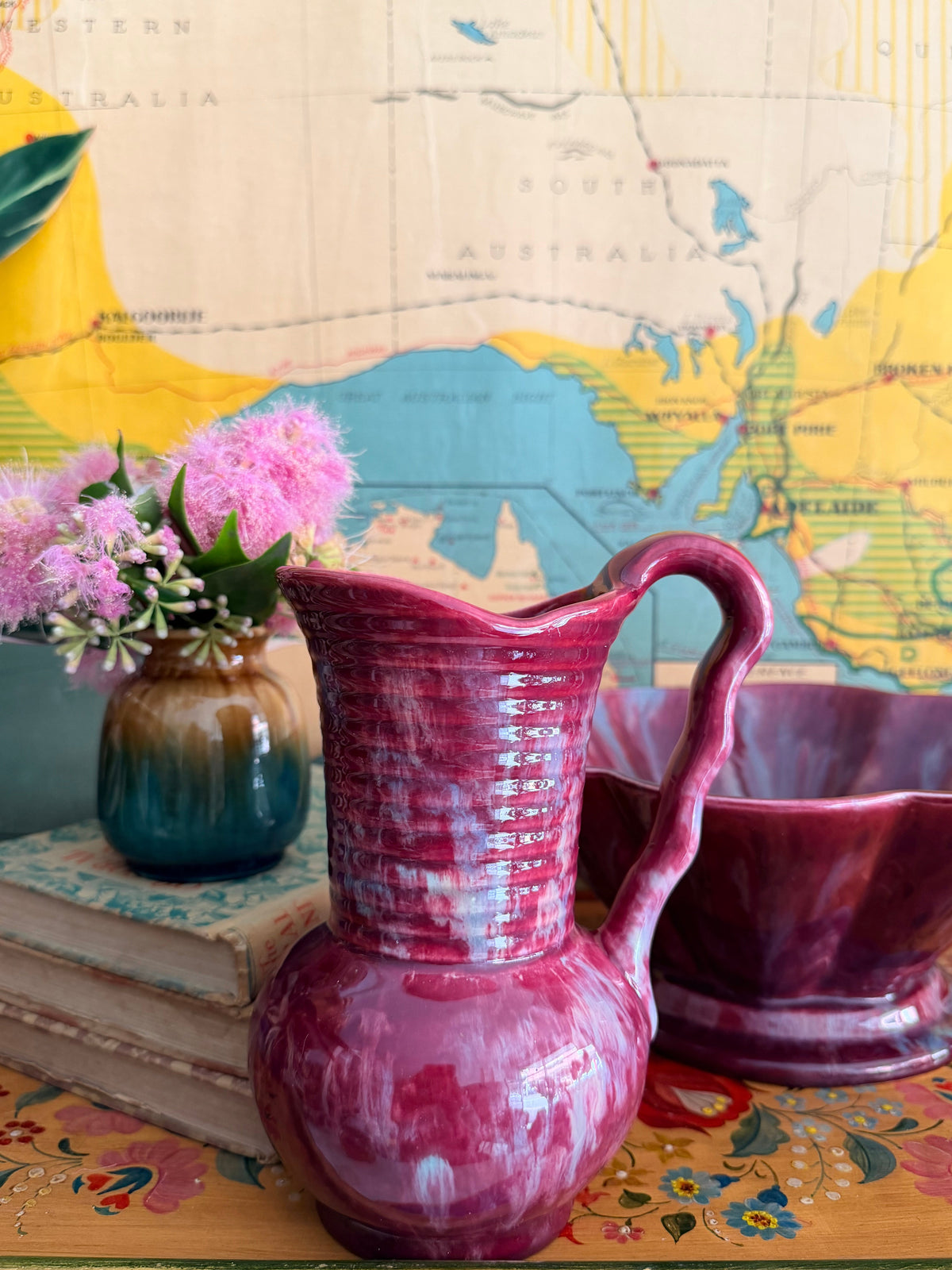 A glossy retro marbled magenta-pink ceramic pitcher with a ribbed neck and curved handle 