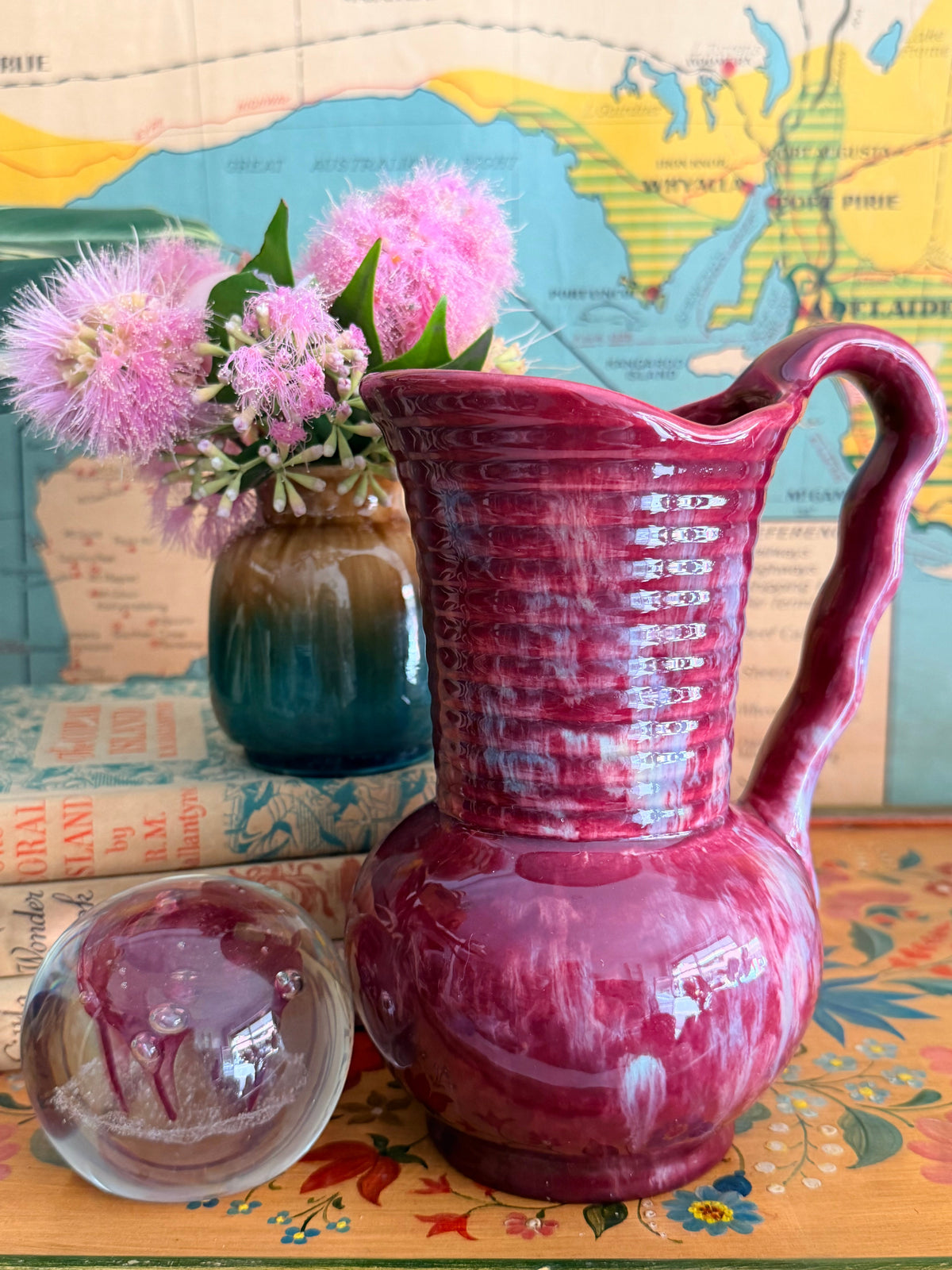 A glossy retro marbled magenta-pink ceramic pitcher with a ribbed neck and curved handle 