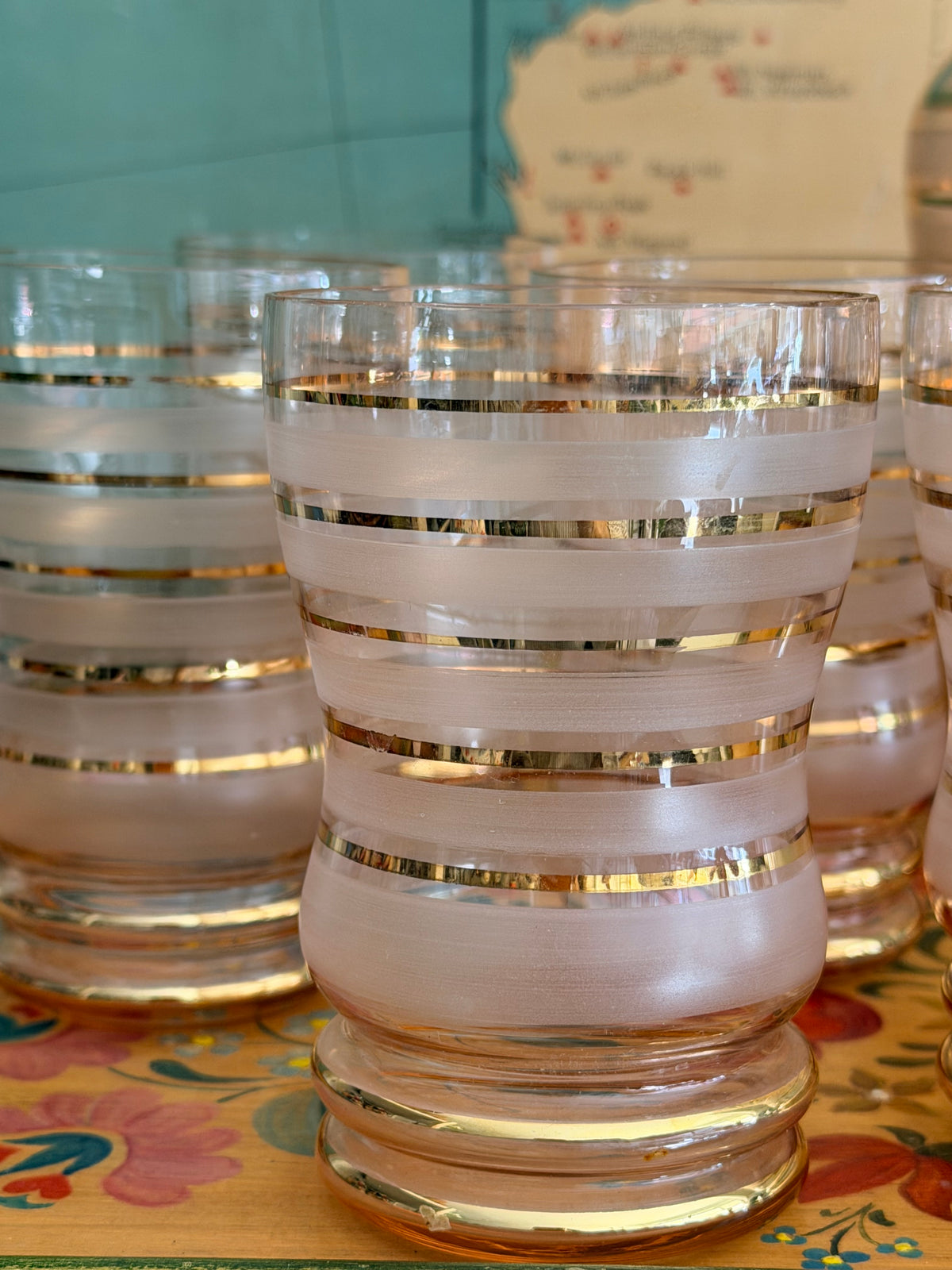 A group of retro vintage aqua blue glass tumblers with etched grape designs and bright blue bases,
