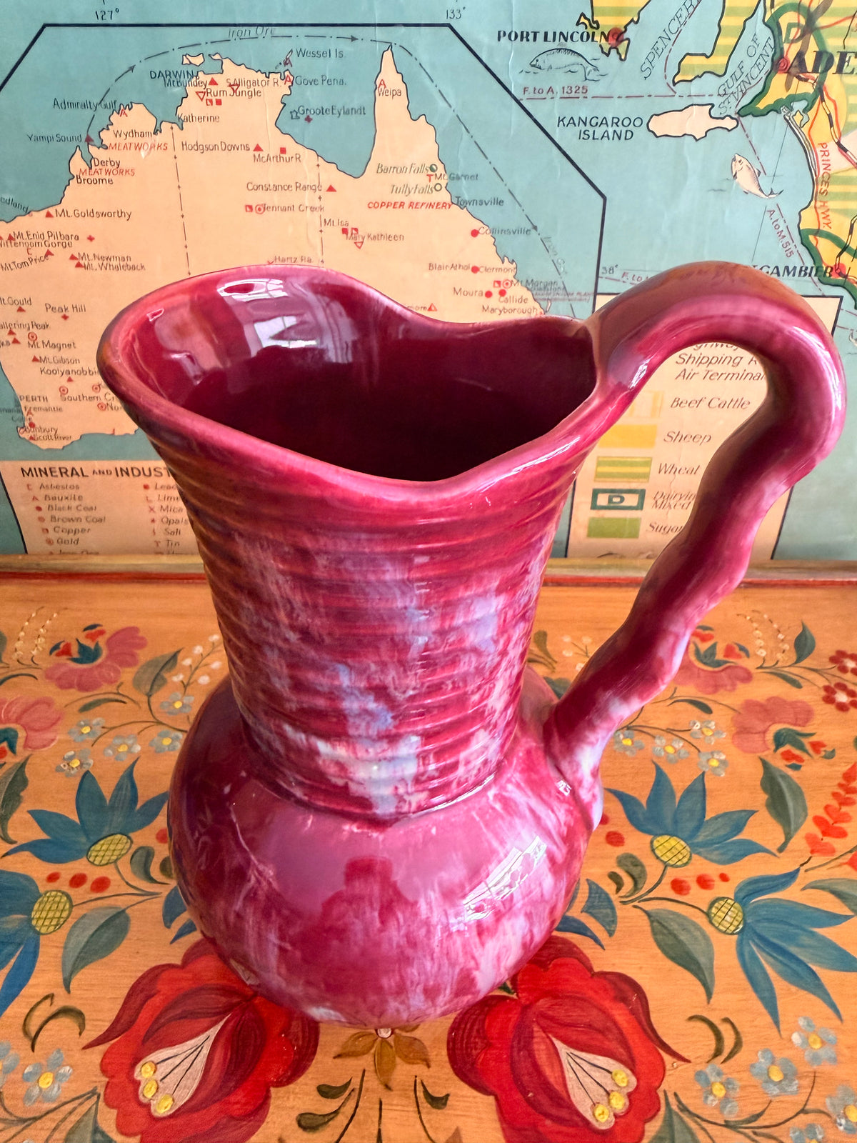 A glossy retro marbled magenta-pink ceramic pitcher with a ribbed neck and curved handle 