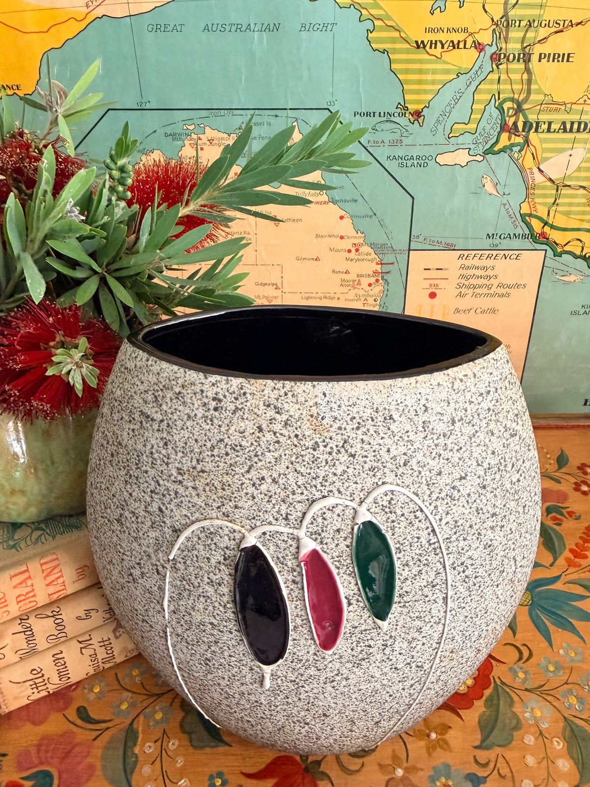 A large mid century speckled gray ceramic planter with three hanging glass clover-like ornaments in black, burgundy, and green