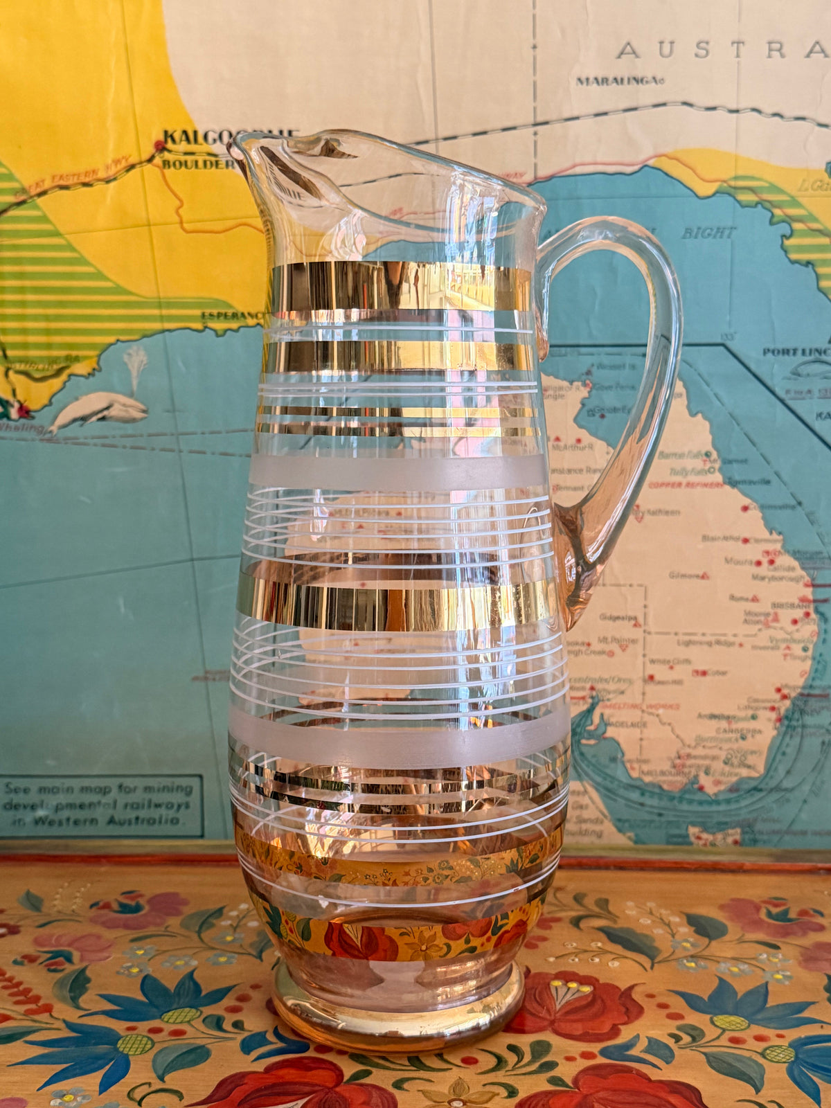 A  retro blush glass pitcher with frosted horizontal bands and shiny gold gilt