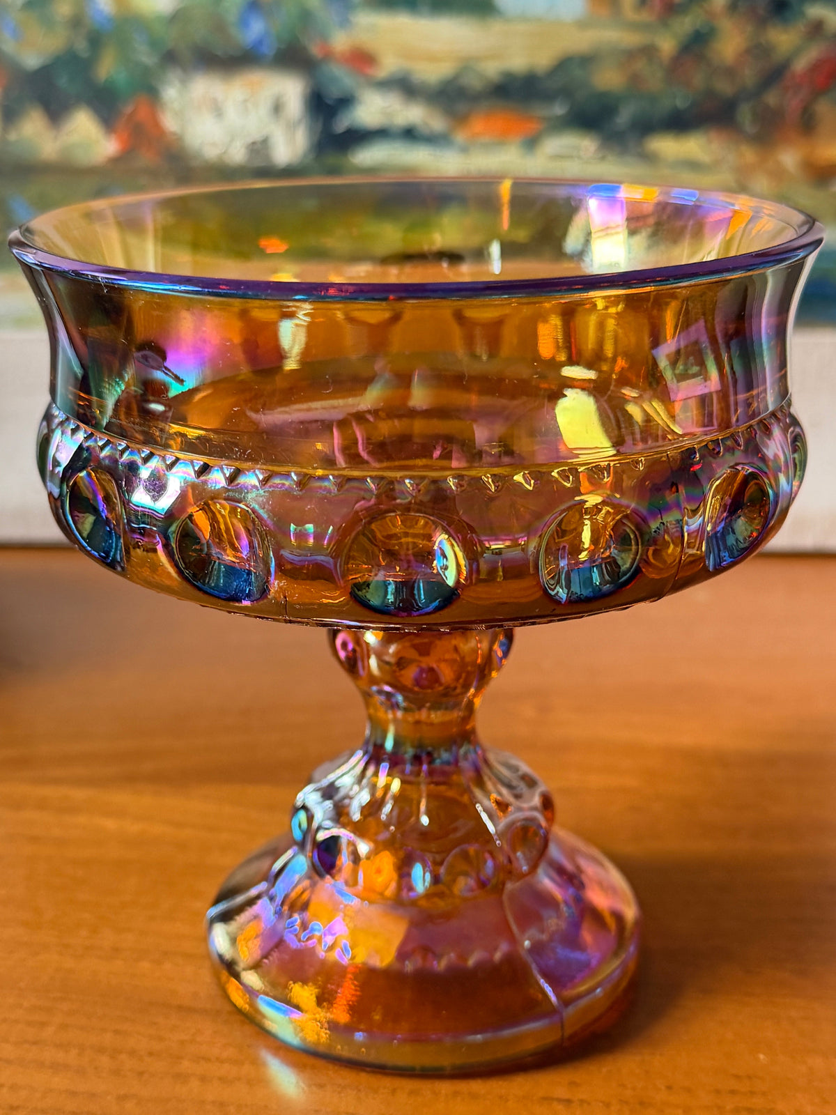 An iridescent carnival glass pedestal bowl , compote, with a gold-amber base and rainbow reflections, 
