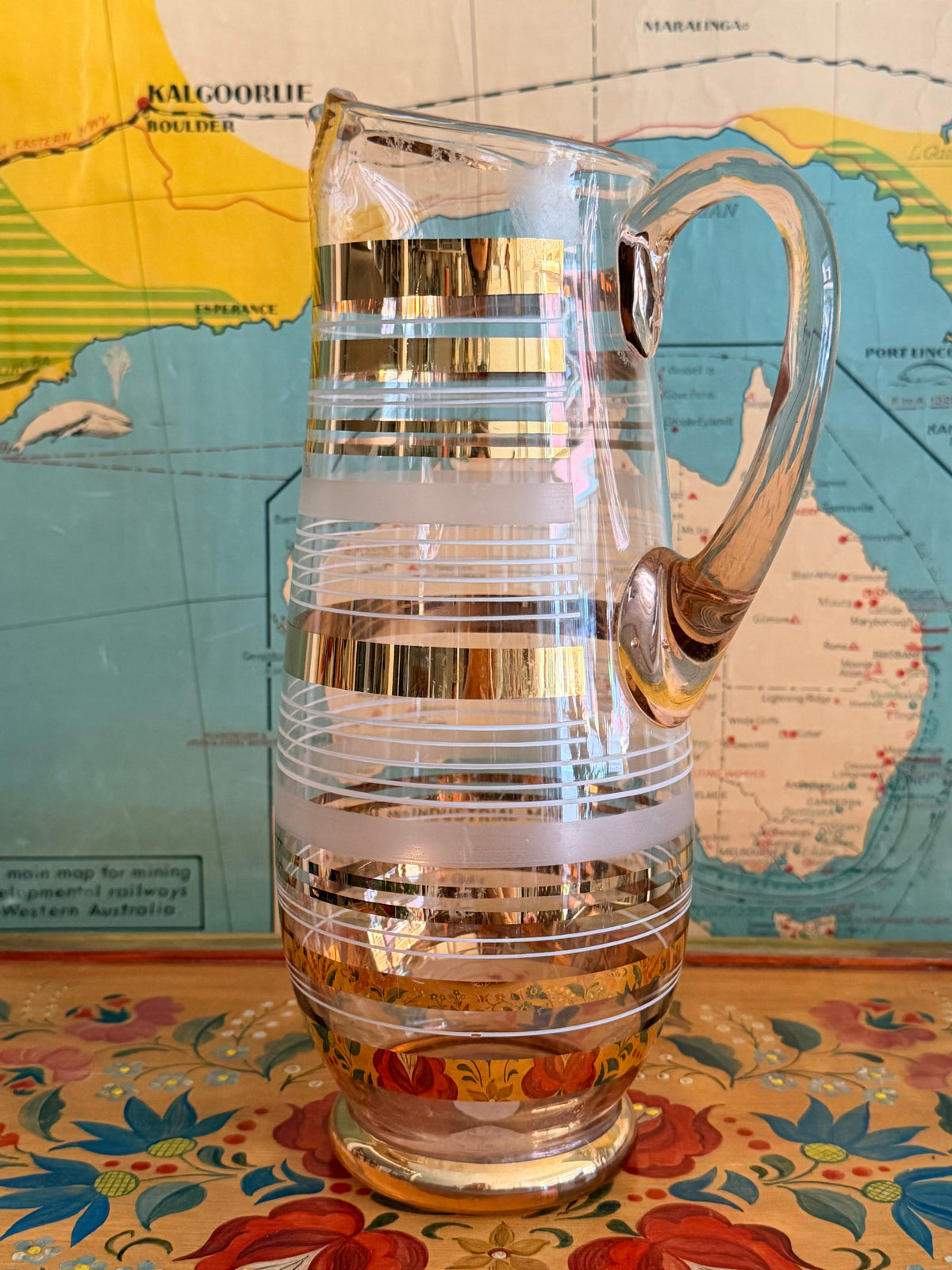 A  retro blush glass pitcher with frosted horizontal bands and shiny gold gilt