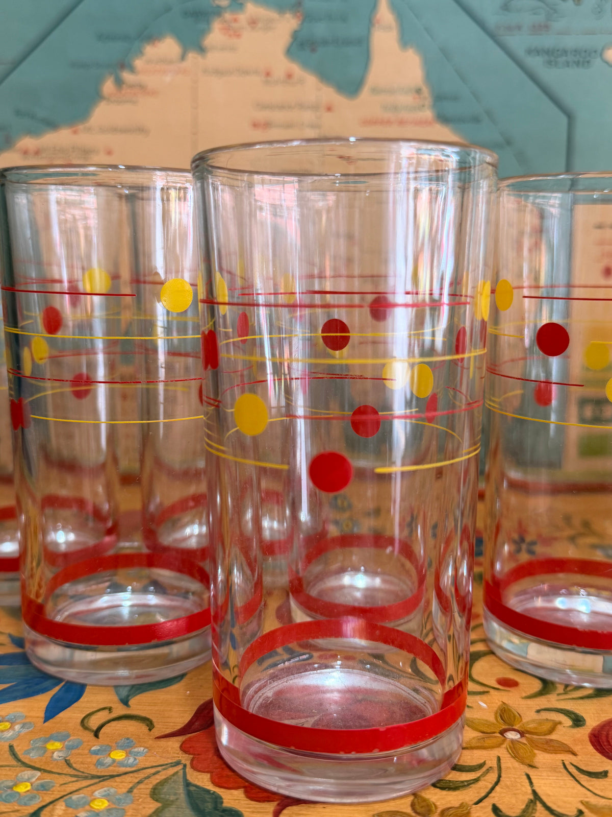 A set of retro clear glass drinking ware, including a large pitcher and six tumblers, decorated with red and yellow polka dots, 