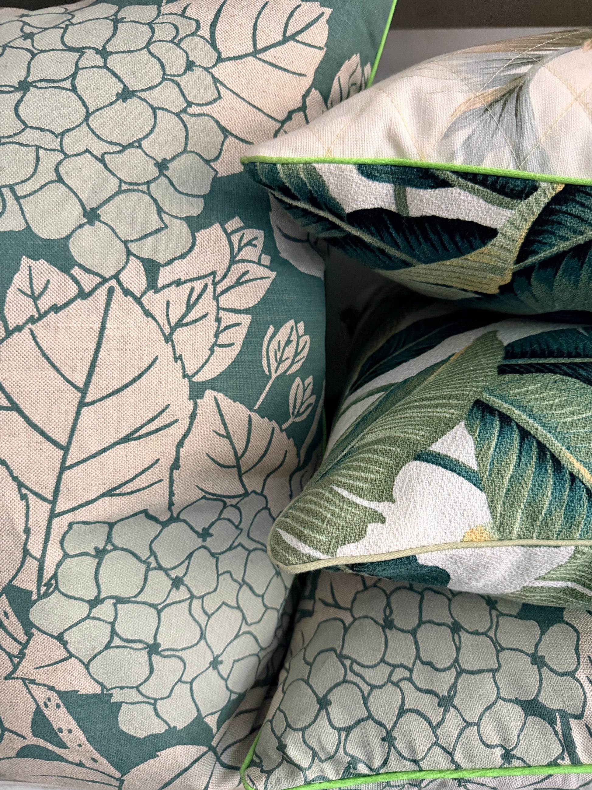 Close-up of decorative pillows with floral and leaf patterns on a fabric surface.