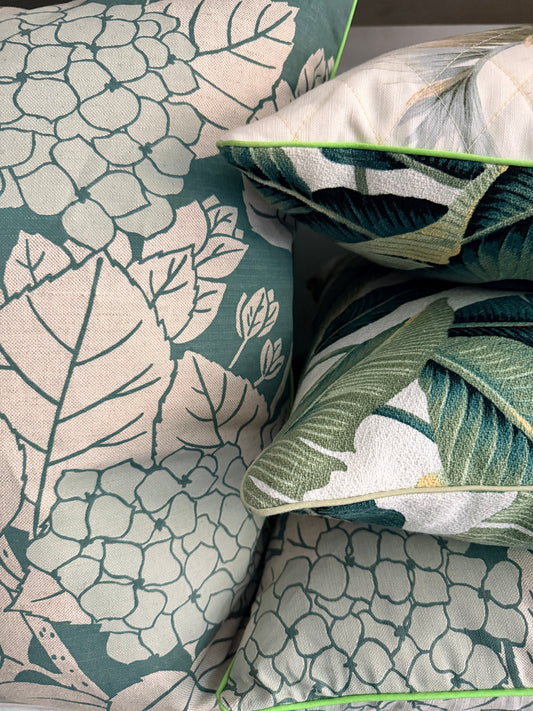 Close-up of decorative pillows with floral and leaf patterns on a fabric surface.