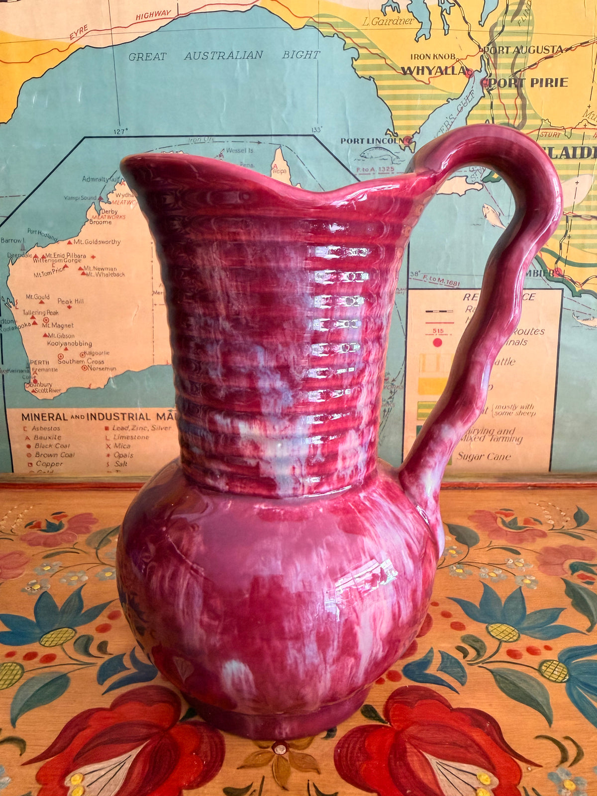 A glossy retro marbled magenta-pink ceramic pitcher with a ribbed neck and curved handle 