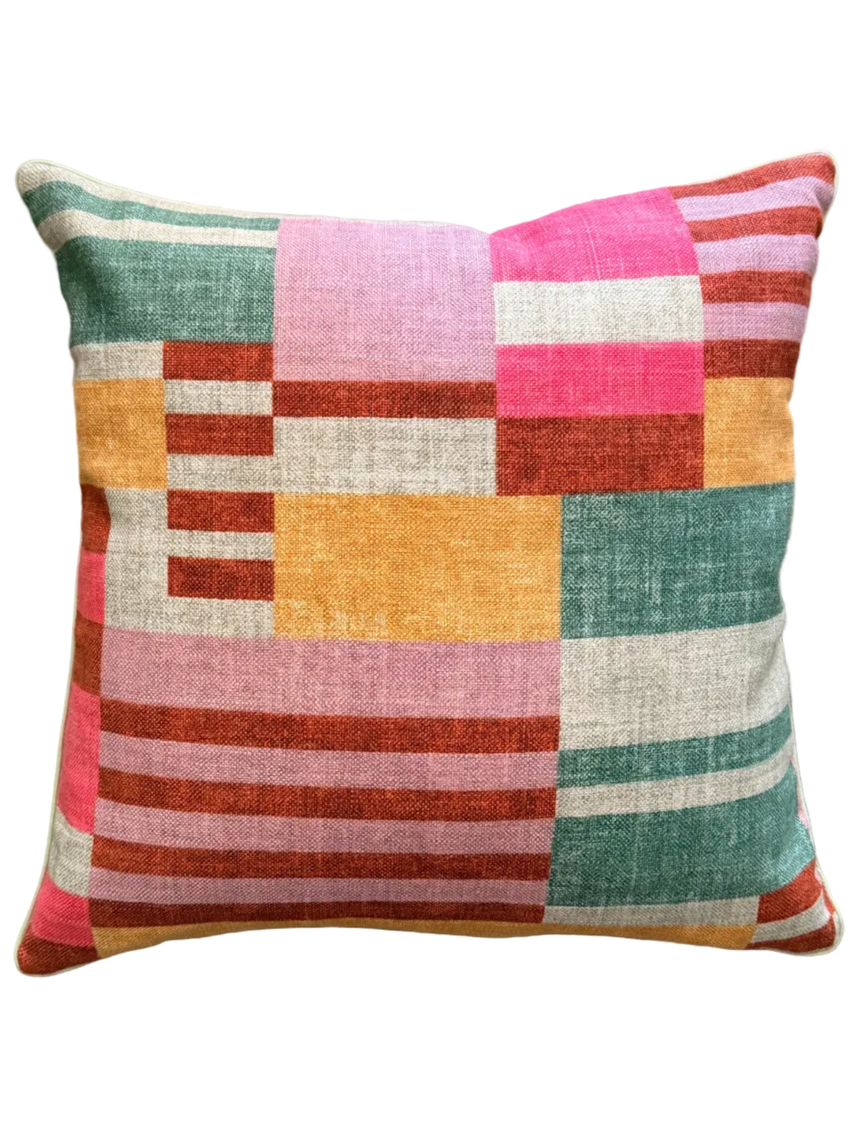 A square throw pillow with a colorful geometric patchwork pattern of stripes and blocks in pink, teal, rust red, mustard yellow, and cream, resting on a textured beige woven rug.