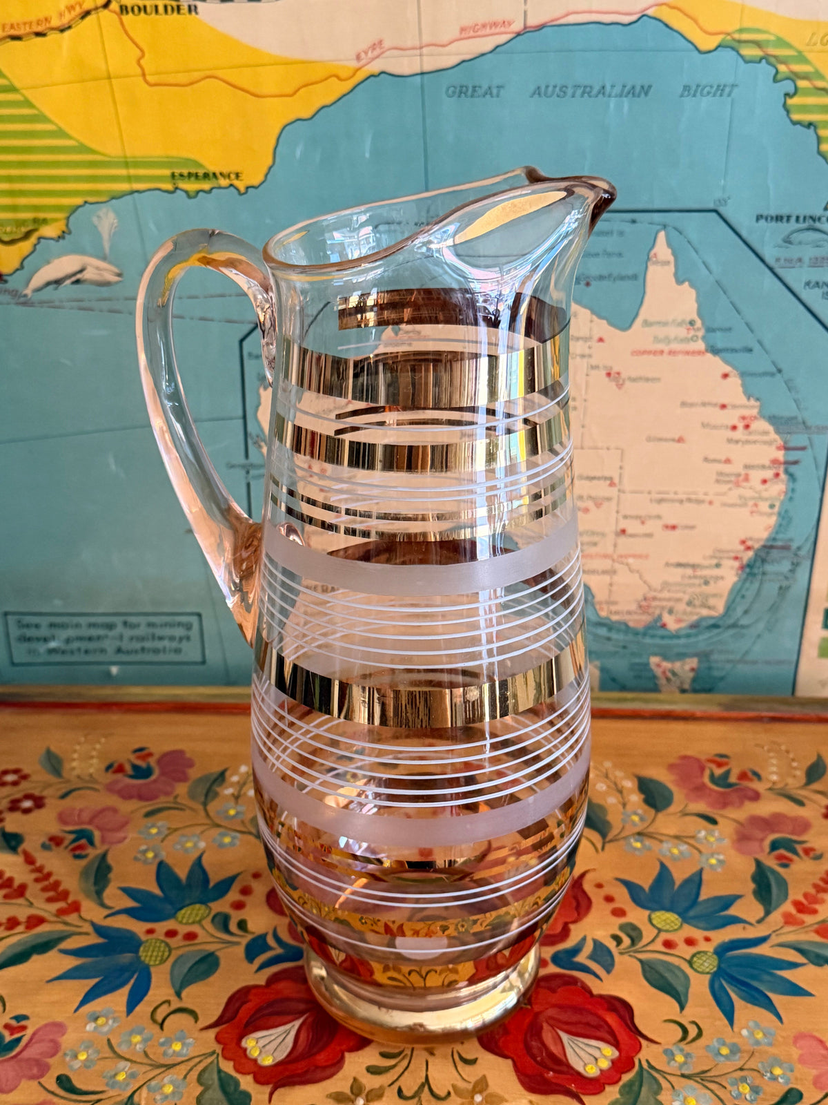 A  retro blush glass pitcher with frosted horizontal bands and shiny gold gilt