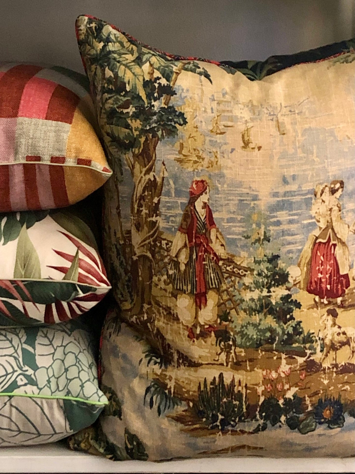 Decorative pillows with intricate patterns, including a classical scene and striped design.