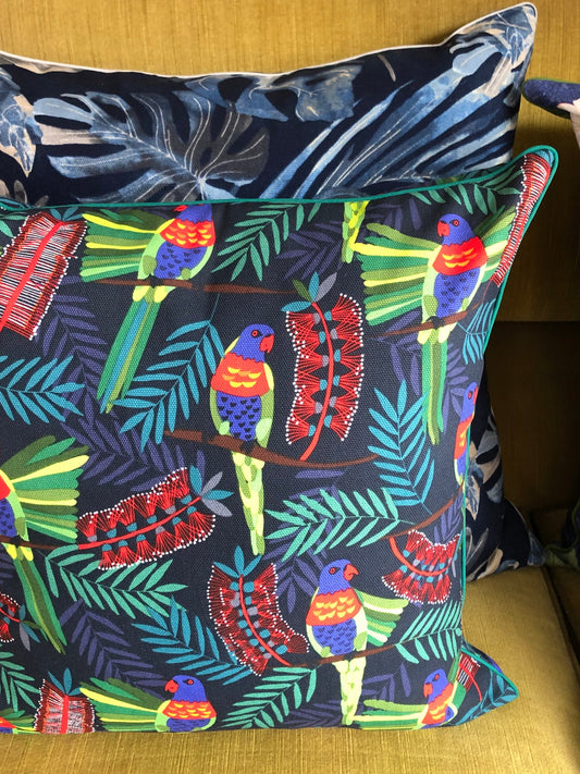 Decorative pillow with tropical bird and leaf pattern on a couch.
