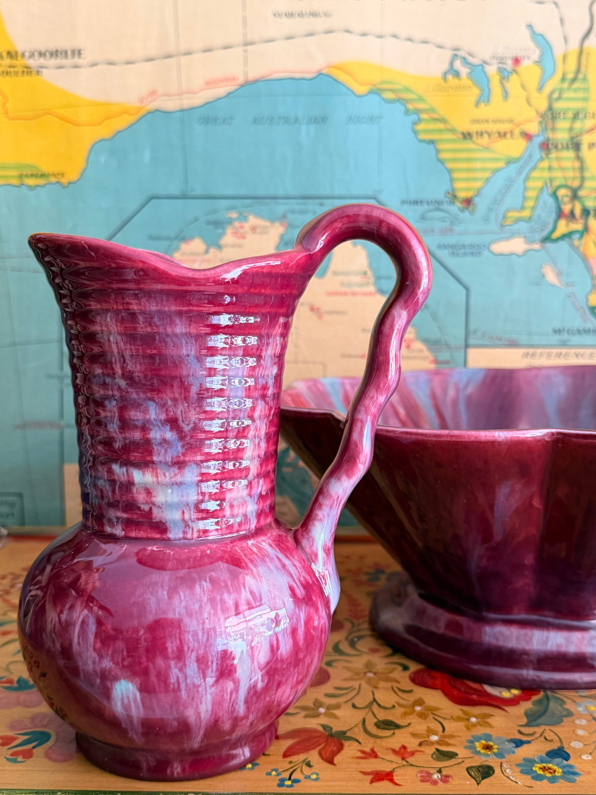 A glossy retro marbled magenta-pink ceramic pitcher with a ribbed neck and curved handle 