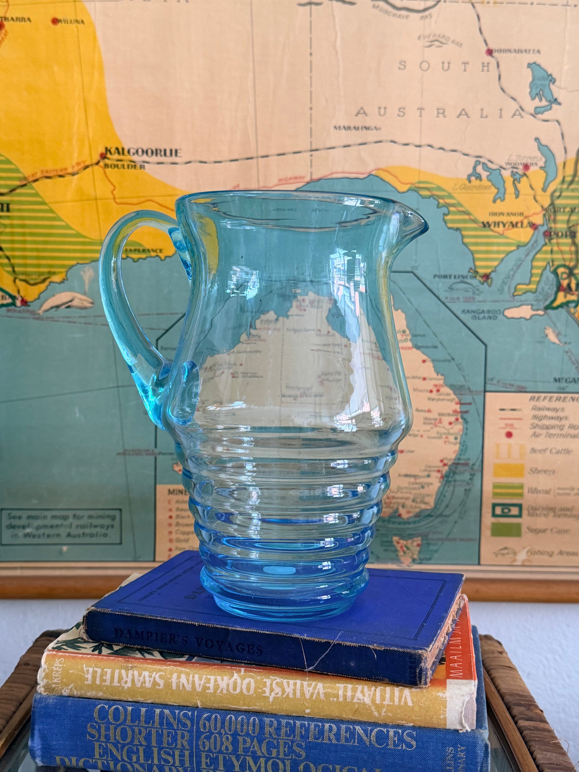 Blue glass pitcher on a stack of books with a world map in the background