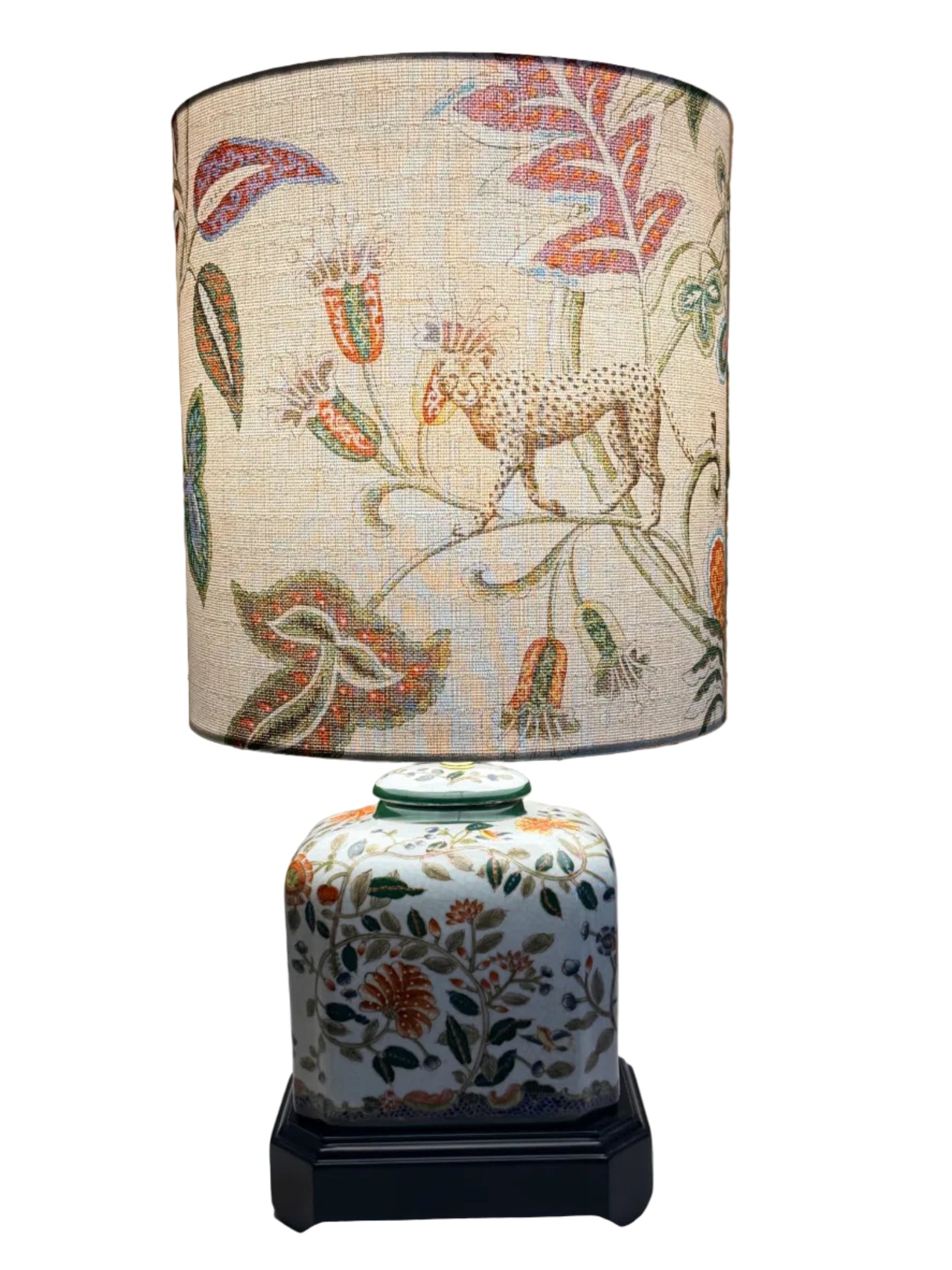 A pair of vintage-style table lamps with white fabric drum shades featuring a colorful botanical and animal print, and matching white ceramic jar bases with floral patterns