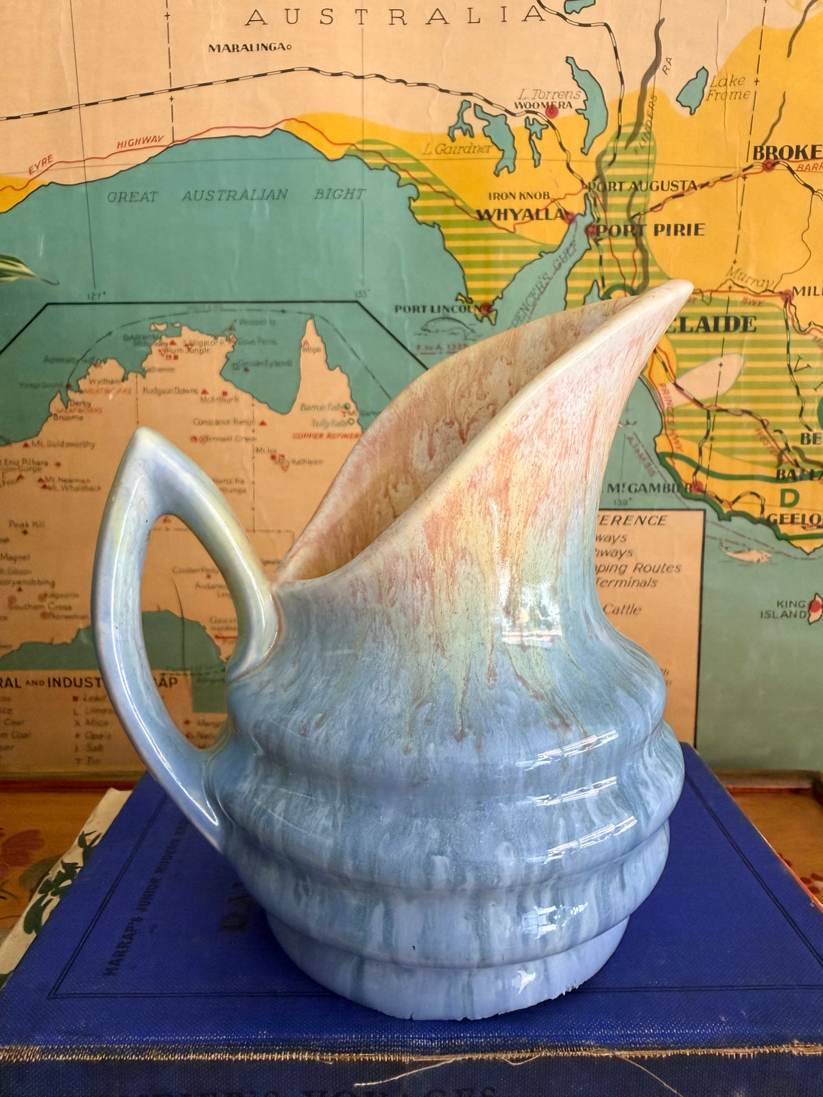 A small ceramic pitcher with a blue and beige marbled drip glaze
