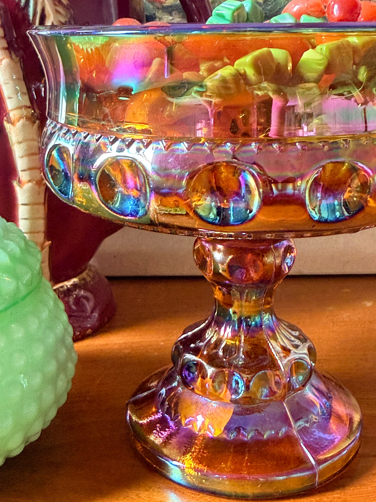An iridescent carnival glass pedestal bowl , compote, with a gold-amber base and rainbow reflections, 