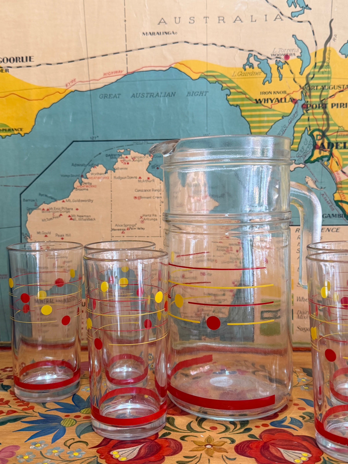 A set of retro clear glass drinking ware, including a large pitcher and six tumblers, decorated with red and yellow polka dots, 