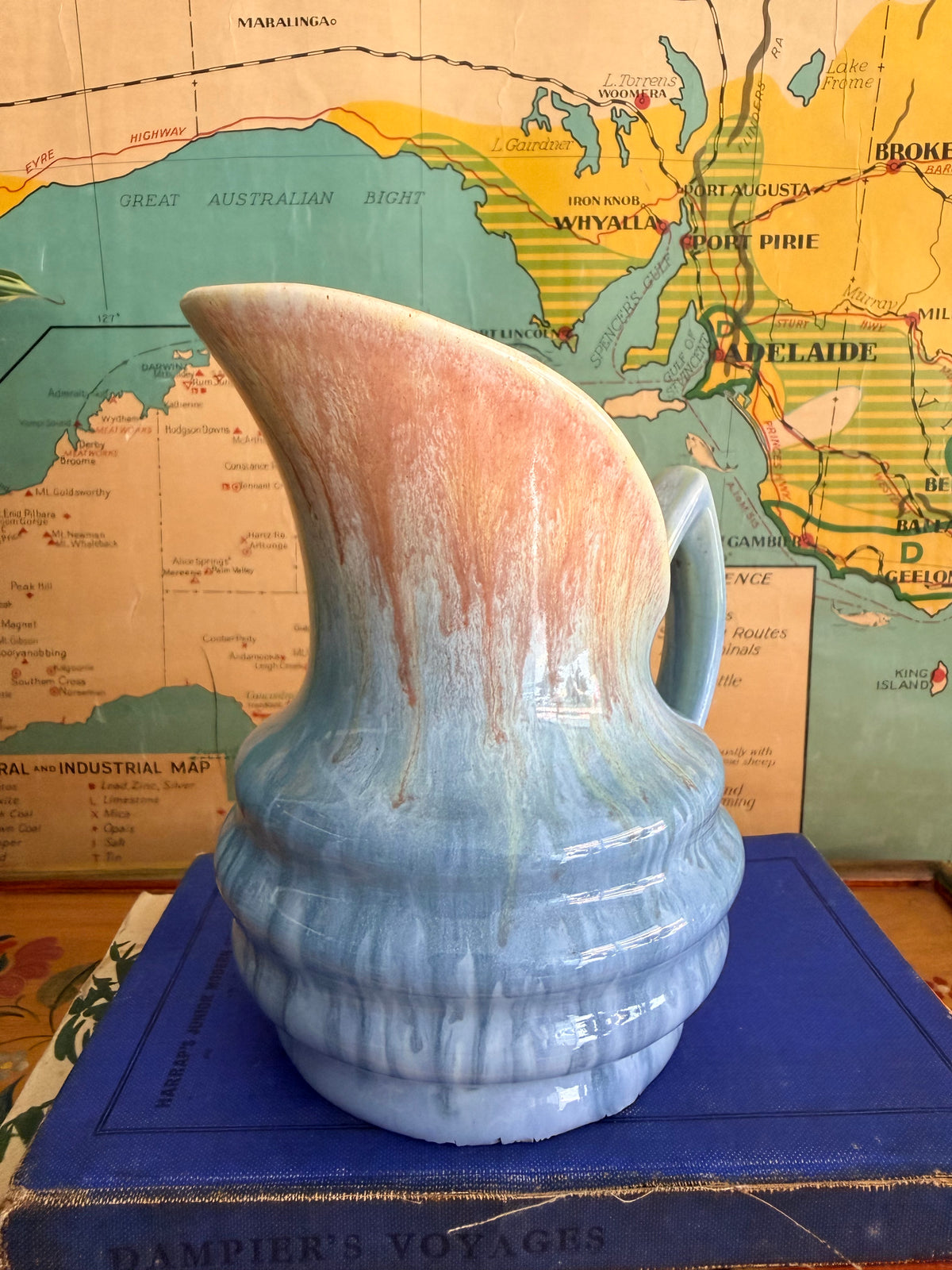 A small ceramic pitcher with a blue and beige marbled drip glaze