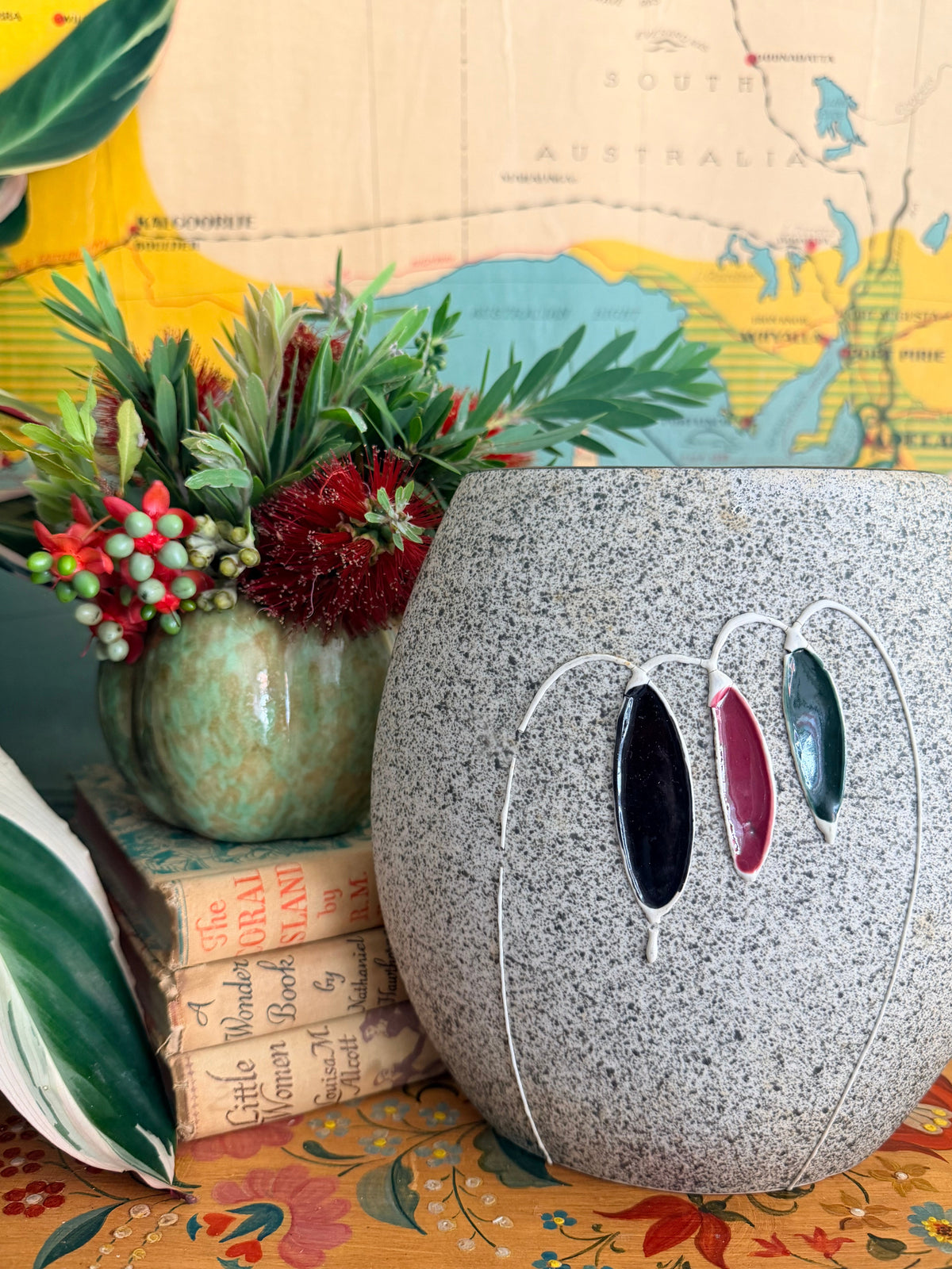 A large mid century speckled gray ceramic planter with three hanging glass clover-like ornaments in black, burgundy, and green