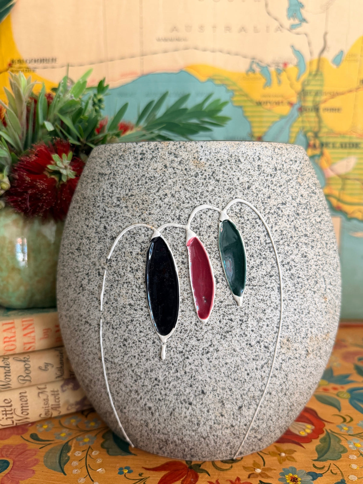 A large mid century speckled gray ceramic planter with three hanging glass clover-like ornaments in black, burgundy, and green